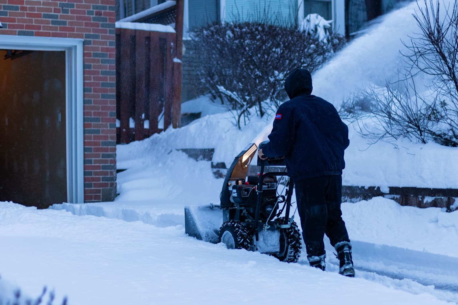Clearing a snow-covered driveway with a two-stage snowblower on a winter evening