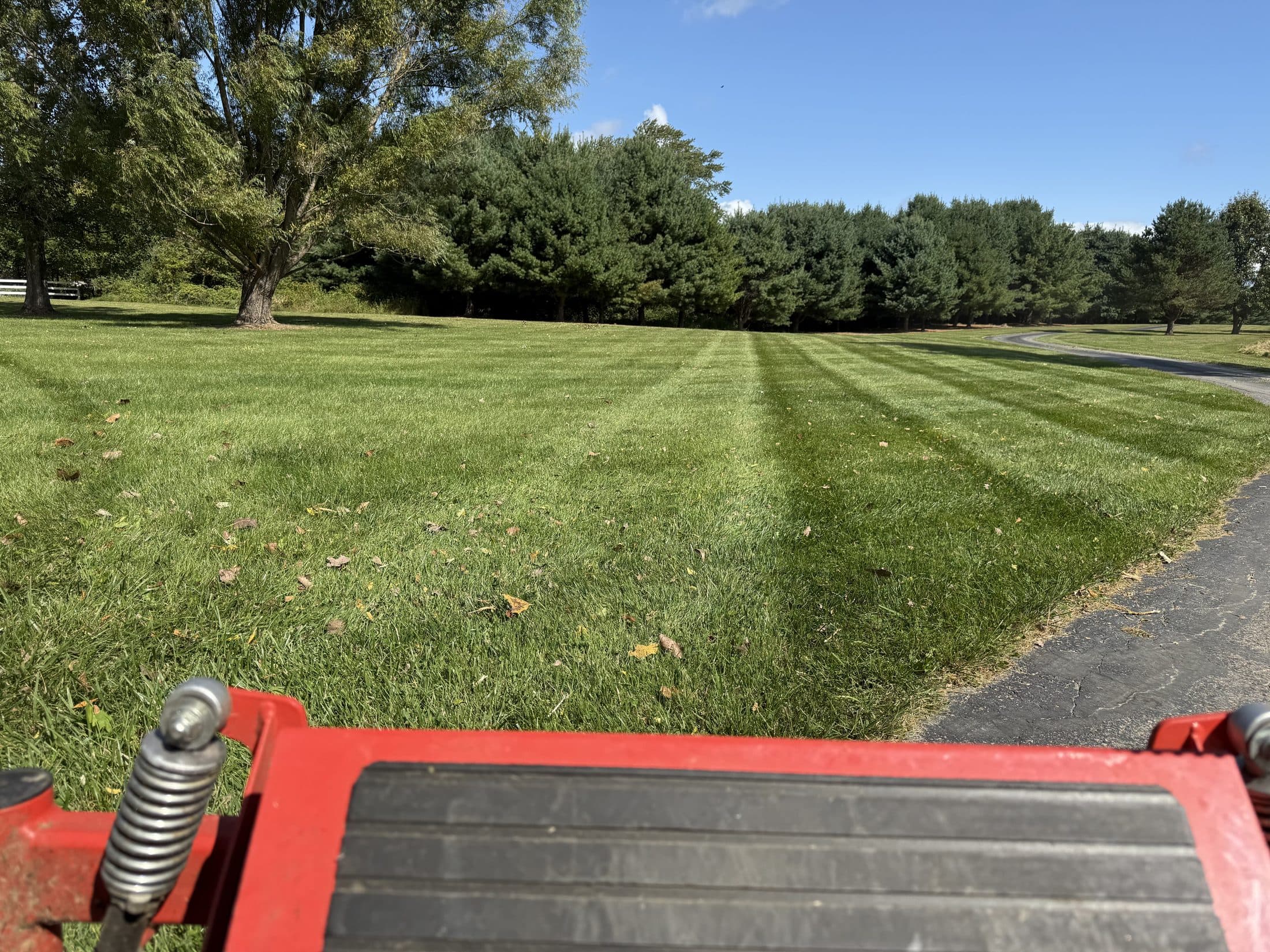 A wide striped lawn seen from behind a riding mower