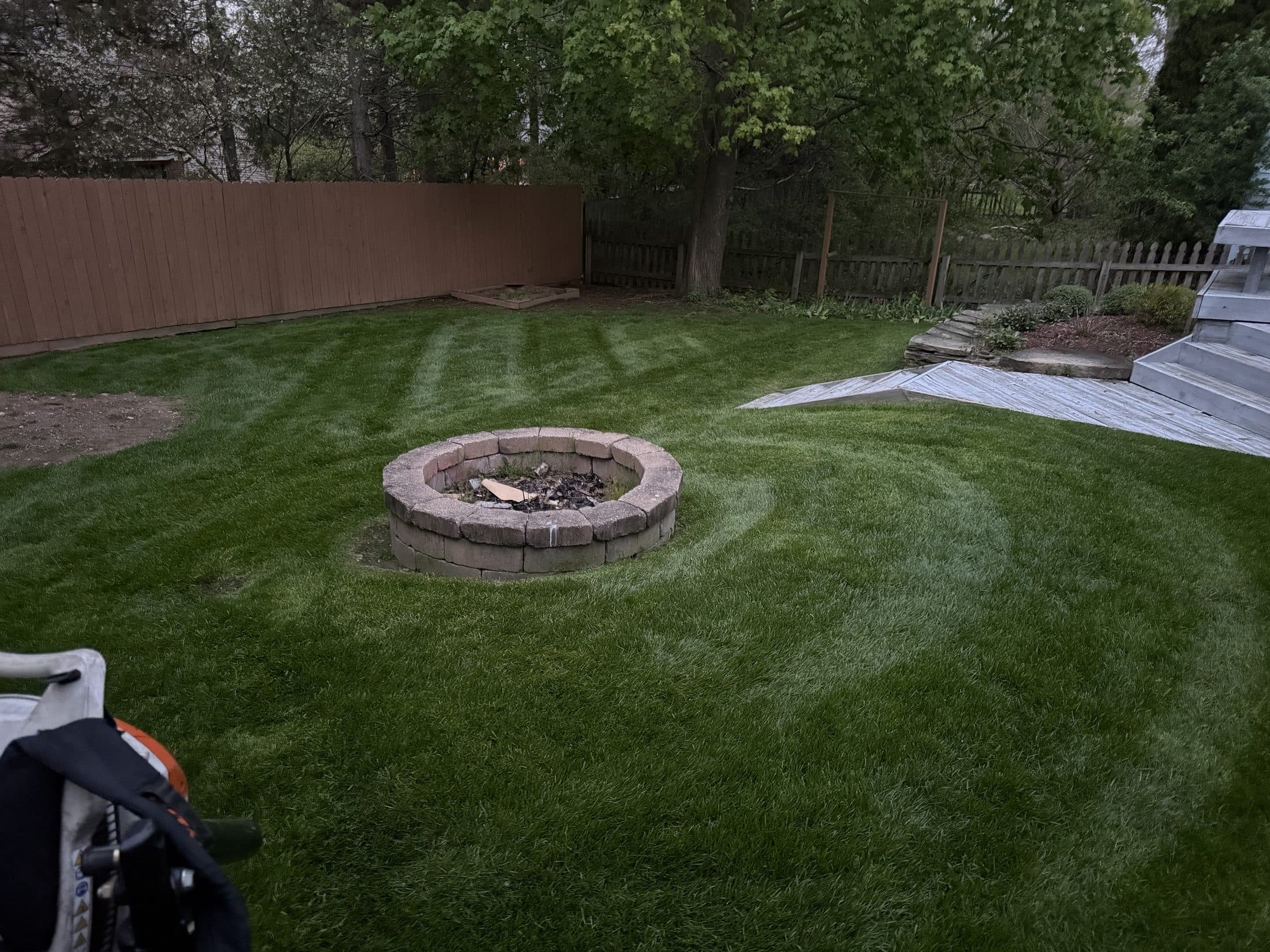 A backyard with a stone fire pit and a tidy, maintained lawn